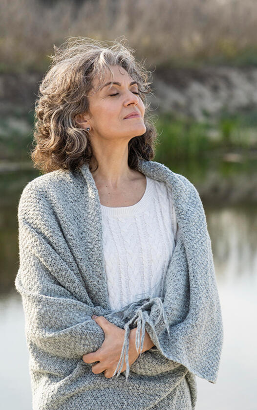 Woman, present in the moment, by a lake, wrapped in a blanket Woman, present in the moment, by a lake, wrapped in a blanket